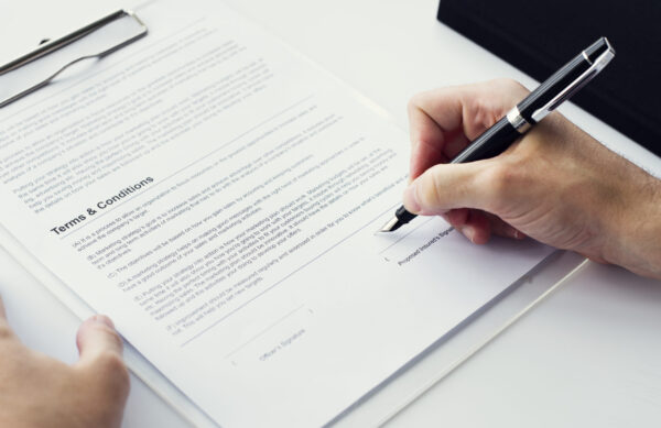 Closeup of hand signing paper workspace Closeup of hand signing paper workspace