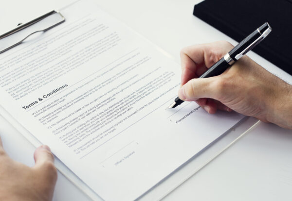 Closeup of hand signing paper workspace